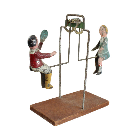 Vintage toy figure on a stand with a plain background