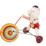 Toy figure of a pig riding a tricycle with colorful wheels on a white background
