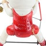 Vintage toy figure with red apron and wheels on a white background