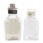 Two glass bottles with silver lids on a white background