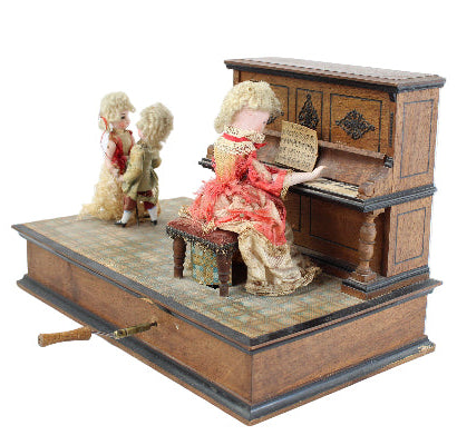 Miniature doll playing a piano with two dolls watching on a white background