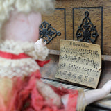 Vintage doll interacting with an old piano and sheet music