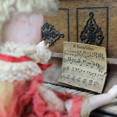 Vintage doll interacting with an old piano and sheet music