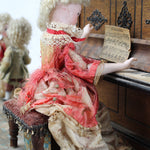 Vintage-style doll with intricate clothing and accessories on a textured surface