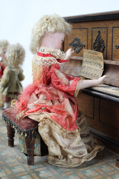 Vintage-style doll with intricate clothing and accessories on a textured surface
