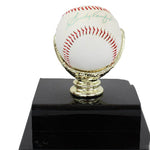 Signed baseball on a black base with gold stand against a white background