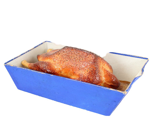 Roasted chicken in a blue roasting pan on a white background