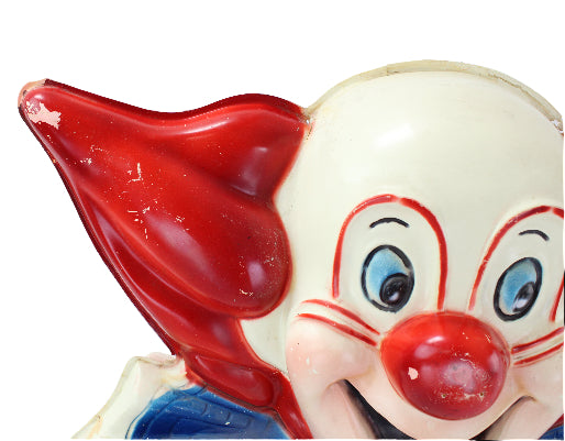 Close-up of a clown figurine with a red nose and blue eyes on a white background