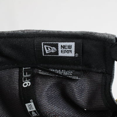 Close-up of a New Era cap with brand logo and tag on a light gray background