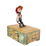 Vintage toy figure on a decorative wooden box against a white background