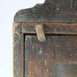 Close-up of a wooden surface with a visible hinge on a light gray background