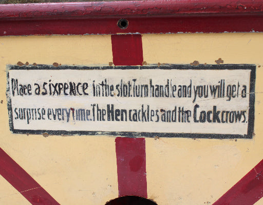 Sign on a mechanical device with text about placing a sixpence for a surprise.