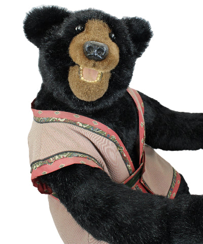 Black bear toy wearing a decorative harness on a white background