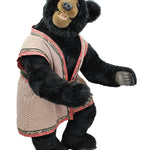 Black teddy bear wearing a pink outfit on a white background