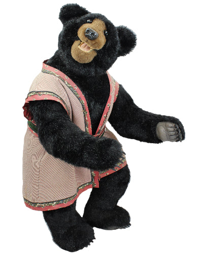 Black teddy bear wearing a pink outfit on a white background