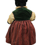 Vintage doll with a green velvet hat and red dress on a white background