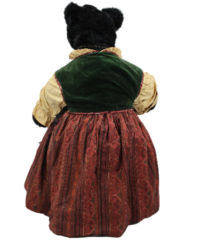 Vintage doll with a green velvet hat and red dress on a white background