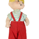 Toy figure with blonde hair, striped shirt, and red overalls on a white background