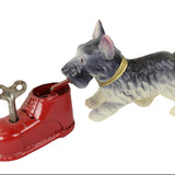 Toy dog standing next to a red shoe with a key on a white background