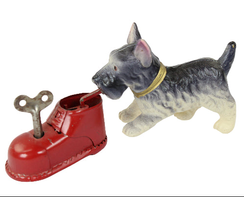 Toy dog standing next to a red shoe with a key on a white background