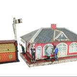 Model train station with small figures and a flag on a white background
