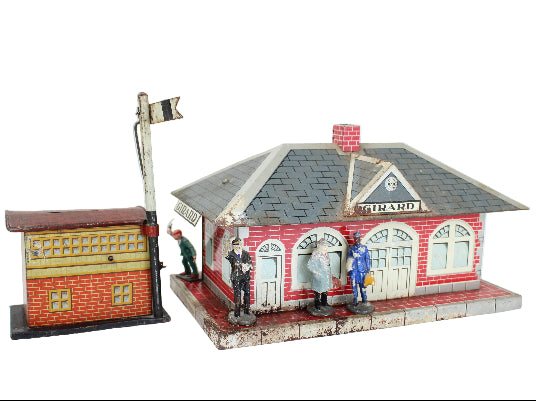 Model train station with small figures and a flag on a white background