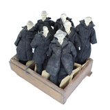 Set of mannequins in dark coats displayed in a wooden crate on a white background