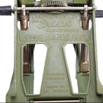 Close-up of a green mechanical device with engraved text on a white background