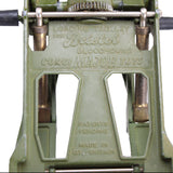 Close-up of a green mechanical device with engraved text on a white background