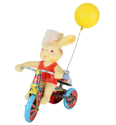 Toy figure of a bear on a unicycle with a yellow ball attached, on a white background
