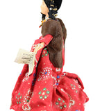 Doll with a red dress featuring floral patterns on a white background