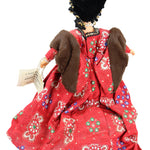 Traditional doll in a red outfit with intricate patterns on a white background