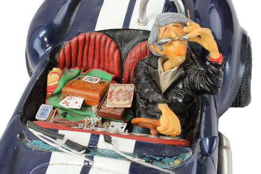 Decorative figurine of a man playing cards in a car with a white background