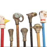 Collection of vintage walking sticks with decorative animal heads on a white background
