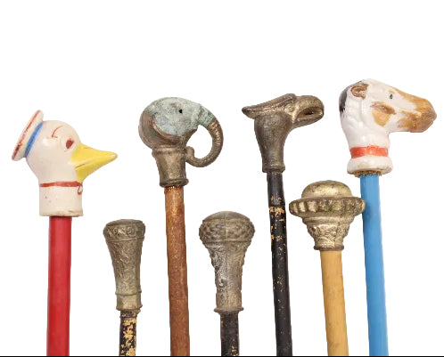 Collection of vintage walking sticks with decorative animal heads on a white background