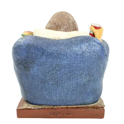Statue of a person sitting on a blue couch with a white background
