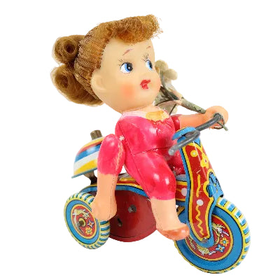Toy figure of a girl on a tricycle with a colorful design on a white background