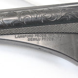 Close-up of a gun stock with engraved details and branding on a white background