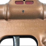 Close-up of a brass toy gun with 'Atomic Model' branding on a light blue background