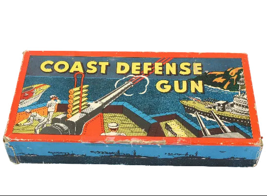 Vintage toy box labeled 'Coast Defense Gun' with colorful graphics on a white background