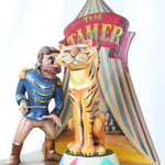 Carnival ride figure with a tiger and a ringmaster in front of a striped tent.