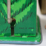 Green metal toy with 'Made in Japan' text on a white surface