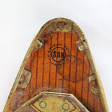 Close-up of a wooden surfboard with 'Sam' branding on a white background