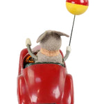 Small red toy car with a plush animal driver and a yellow and red ball on a white background