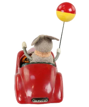Small red toy car with a plush animal driver and a yellow and red ball on a white background