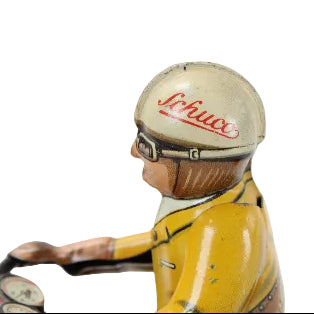 Vintage tin toy figure of a driver with a helmet and Schuco logo and yellow outfit on a white background