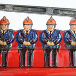 Four toy firemen figures sitting on a red fire truck toy.