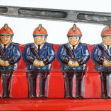 Four toy firemen figures sitting on a red fire truck toy.