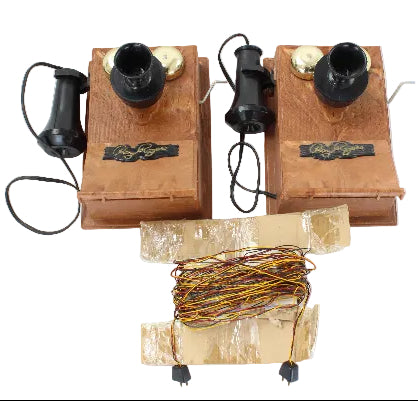 Two vintage wall-mounted telephones with coiled wires on a white background