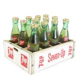 Vintage Seven-Up bottles in a wooden crate on a white background